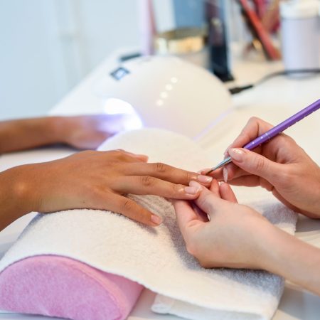 Close-up of beautician painting a woman’s nails with a brush in femme faisant une manucure