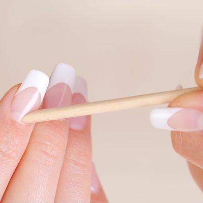 Female cleaning cuticle on hands Female cleaning cuticle on hands with a cosmetic stick - macro shot and soft focus