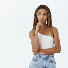 I wonder what friends do. Thoughtful gloomy and spaced out cute african-american female with dreadlocks in white top holding hand on chin gazing at upper left corner while thinking nostalgic femme qui réfléchit