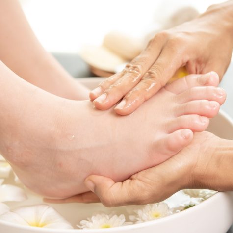 foot washing in spa before treatment. spa treatment and product foot washing in spa before treatment. spa treatment and product for female feet and hand spa. white flowers in ceramic bowl with water for aromatherapy at spa.